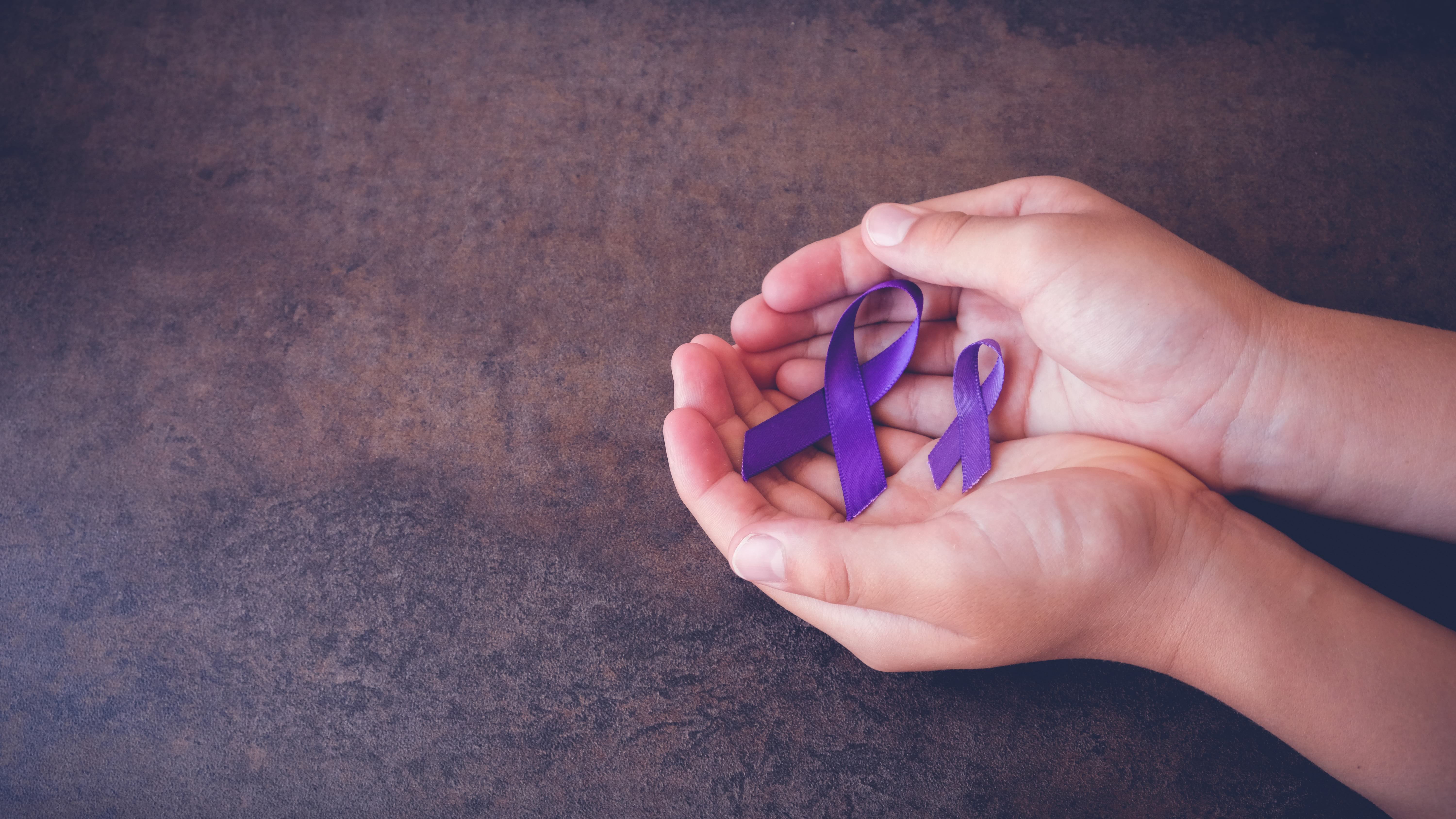 Hands holding purple ribbons